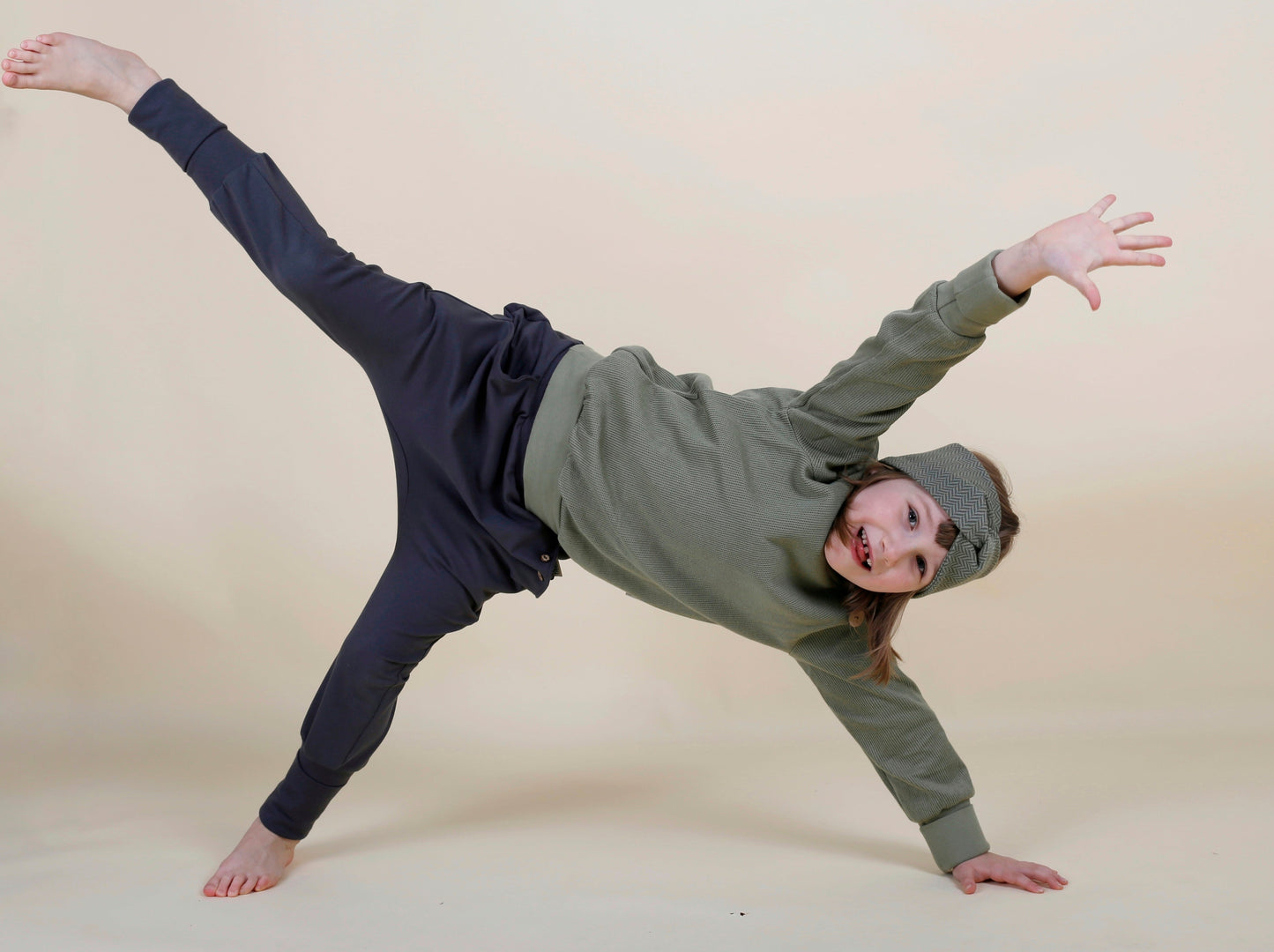 Kind albert herum und hat grünen Pullover und graue Hose an