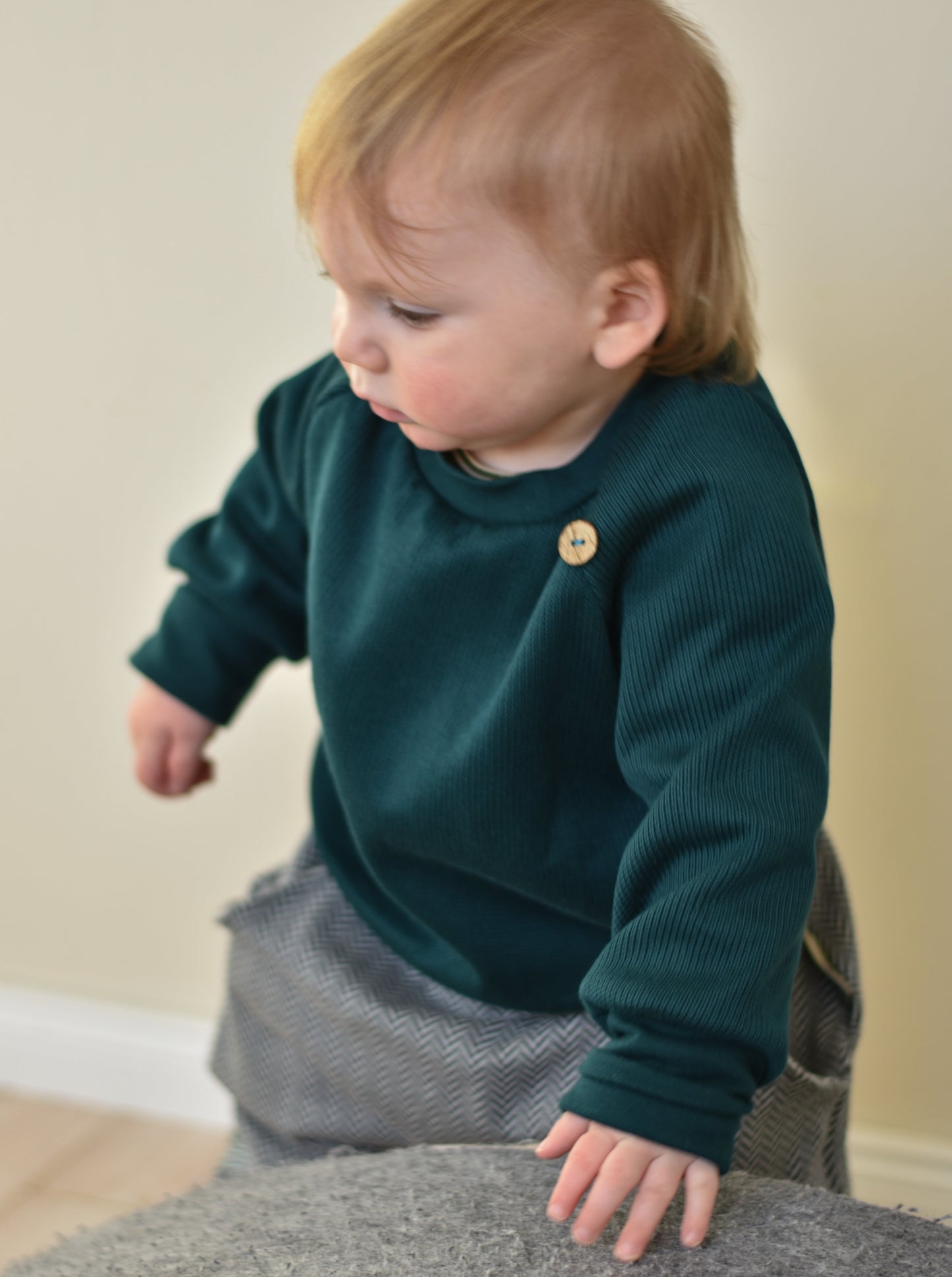 Baby hat einen lauen Pullover aus Strick an
