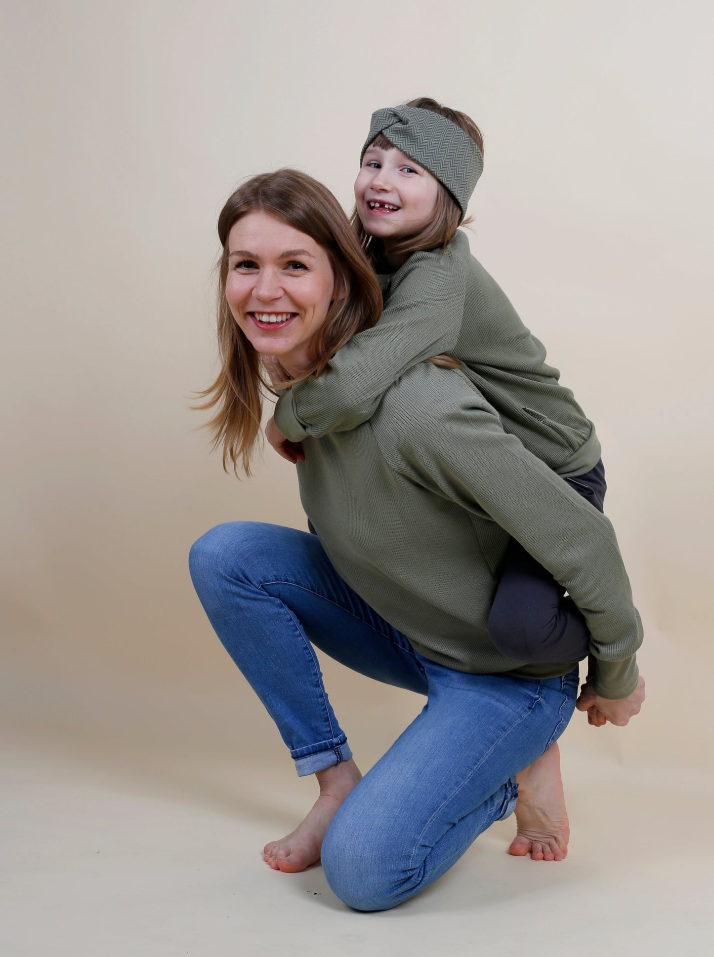 Eine Frau trägt ein Mädchen auf dem Rücken und sind im Partnerlook