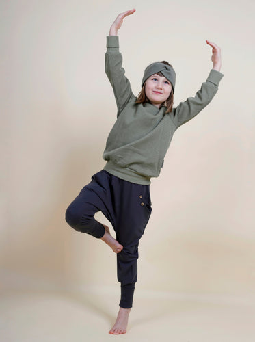 Kind macht eine Yogapose und trägt bequeme Sachenn