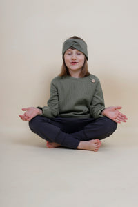 Kind macht Yoga und trägt neutrale Mode