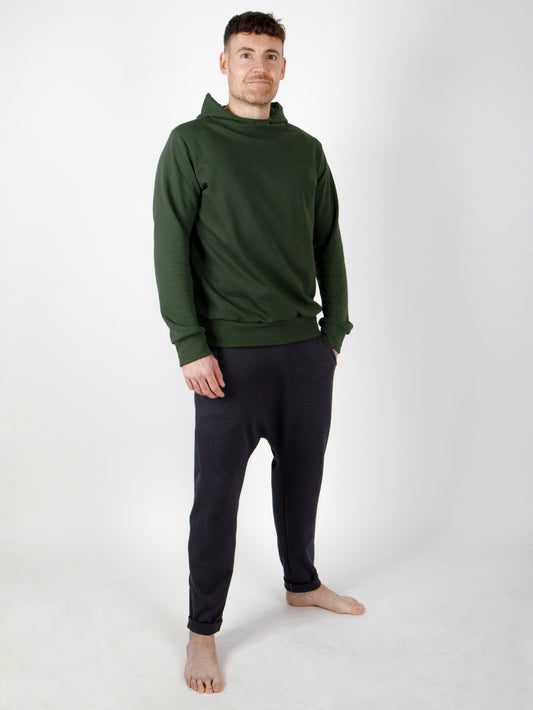 Ein Mann trägt eine Herrenhose und ein Oberteil für Herren mit Kapuze aus zertifizierter Biobaumwolle