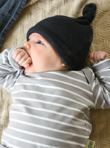 Baby trägt eine schwarze Knotenmütze passend zur Knotenmütze