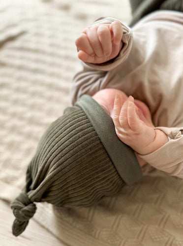 Baby trägt selbstgenähte grüne Knotenmütze aus Biobaumwolle
