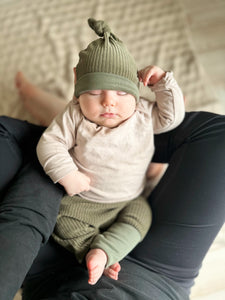 Baby liegt im Schoß seiner Mutter und trägt ein schlichtes Outfit made in Germany