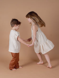 Kinder tanzen und tragen weißes Leinenkleid