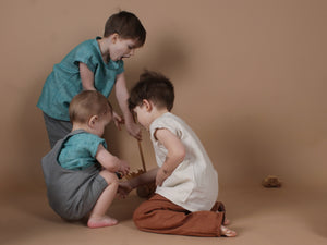 Kinder spielen mit Holzspielzeug und tragen Kleidung aus Leinen