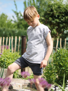 Junge spielt im Garten und trägt ein handgemachtes T-Shirt aus Biobaumwolle