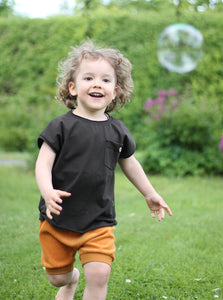 junge spielt mit Seifenblasen und trägt Shorts aus Biobaumwolle