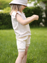 Laden Sie das Bild in den Galerie-Viewer, Ein Kind spielt mit einem Gänseblümchen und trägt eine nachhaltige Shorts aus Biobaumwolle